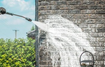 A specialist performing brick house pressure washing.