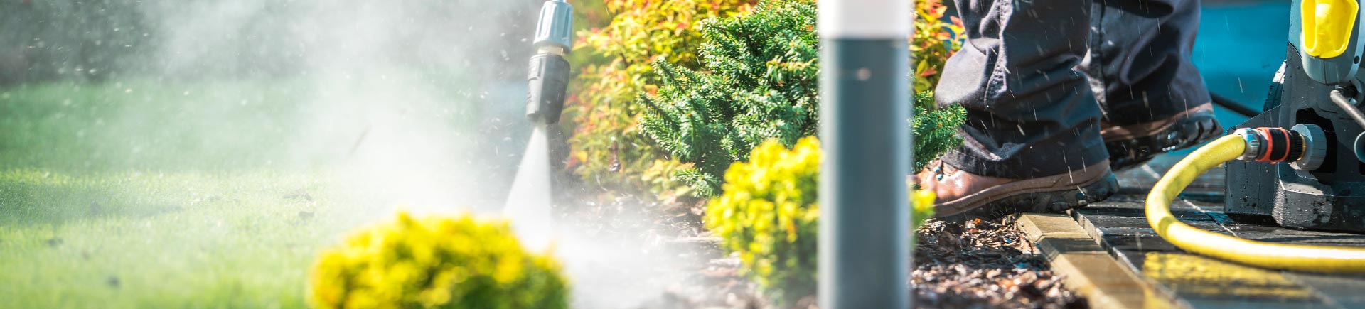 A specialist pressure washing the exterior surface around a gas station.