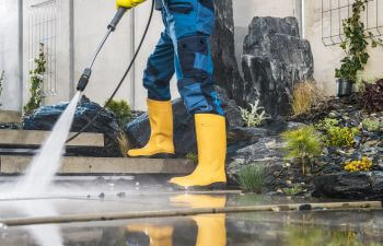 A technician performing outdoor surfaces pressure washing.